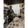 Laszlo from BeesFriend cutting fresh honeycomb into portions in a commercial kitchen, with packed comb sections ready for sale