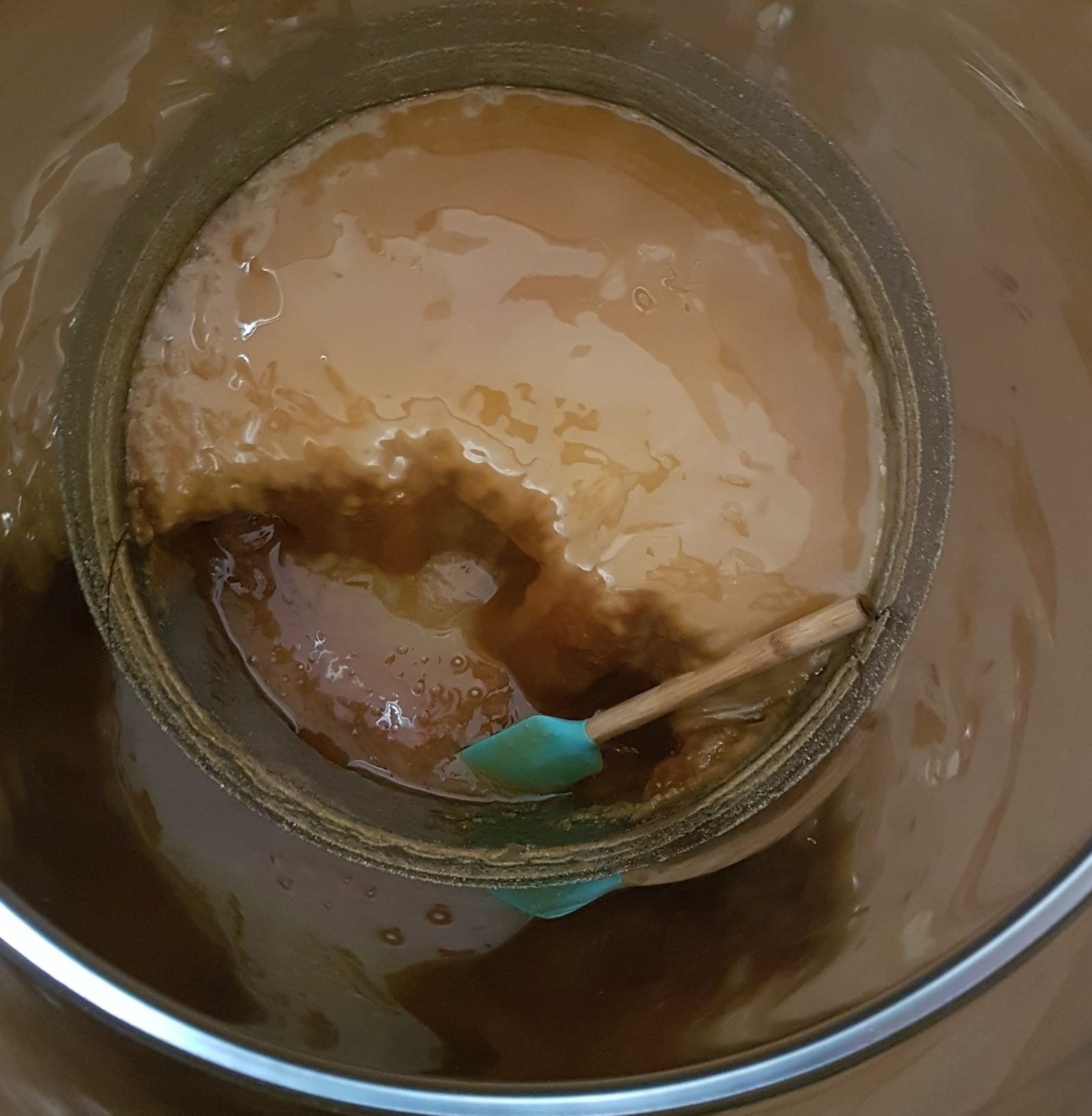 Raw honey part-crystallised in the settling tank, the pale set layer against the runny honey