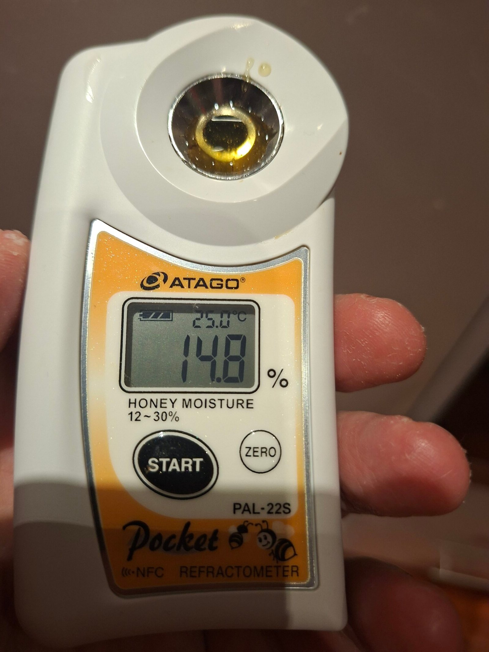 A digital honey refractometer reading 14.8% moisture on a batch of our raw honey